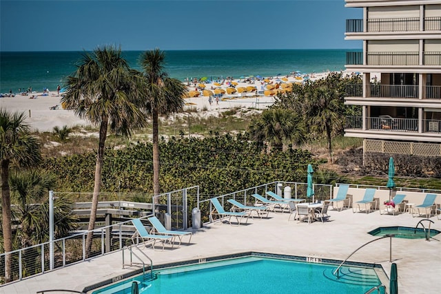 pool featuring a view of the beach, fence, and a water view