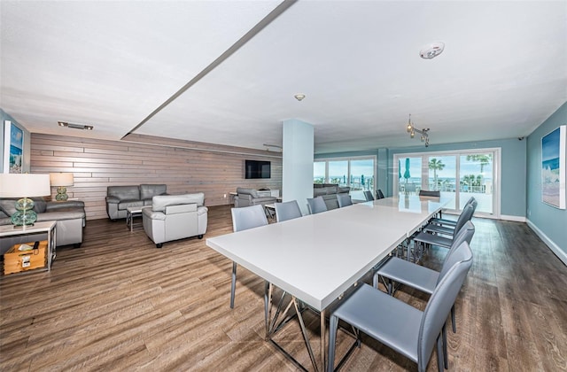 dining area with baseboards, wooden walls, and wood finished floors