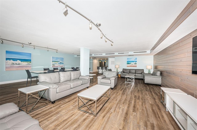 living room with wooden walls, rail lighting, and wood finished floors