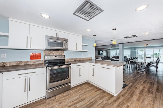 kitchen featuring visible vents, open shelves, a peninsula, stainless steel appliances, and dark countertops