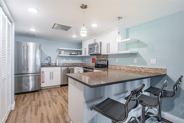 kitchen featuring a peninsula, open shelves, dark countertops, and appliances with stainless steel finishes