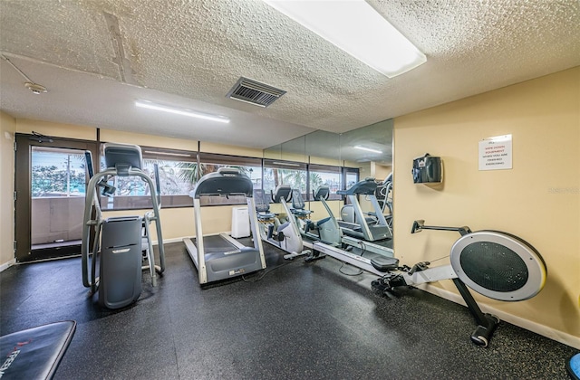 gym featuring visible vents, plenty of natural light, a textured ceiling, and baseboards