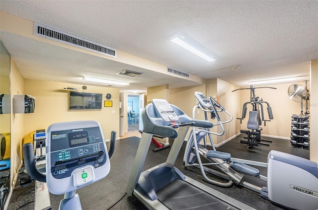 exercise room featuring visible vents, a textured ceiling, and baseboards