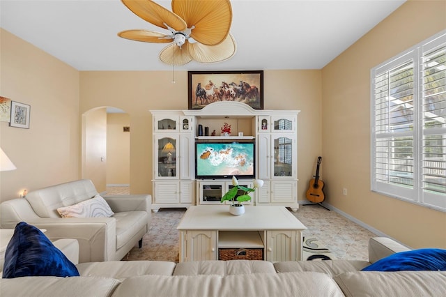 living area featuring arched walkways, light floors, and baseboards