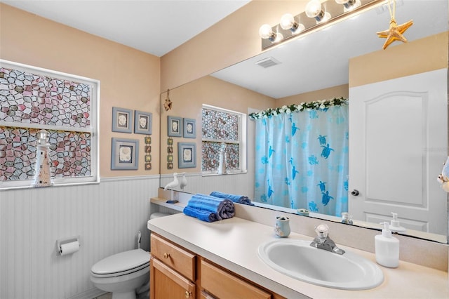 bathroom featuring a wainscoted wall, curtained shower, visible vents, toilet, and vanity