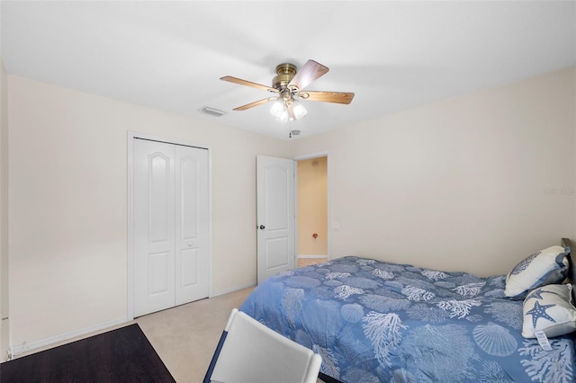 bedroom with ceiling fan, light carpet, visible vents, baseboards, and a closet