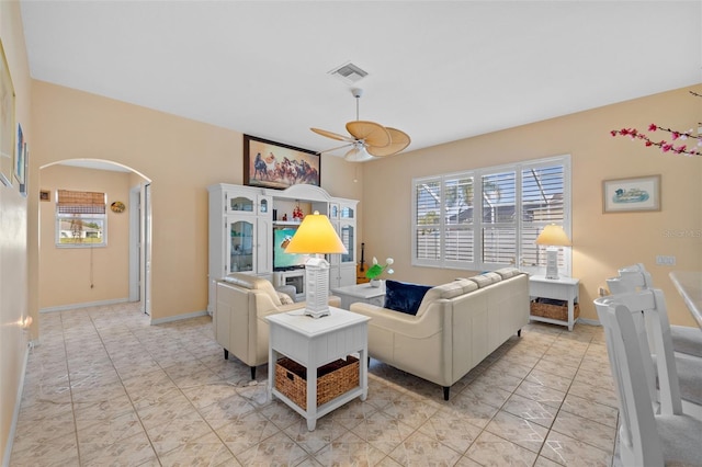 living room with a ceiling fan, arched walkways, visible vents, and baseboards