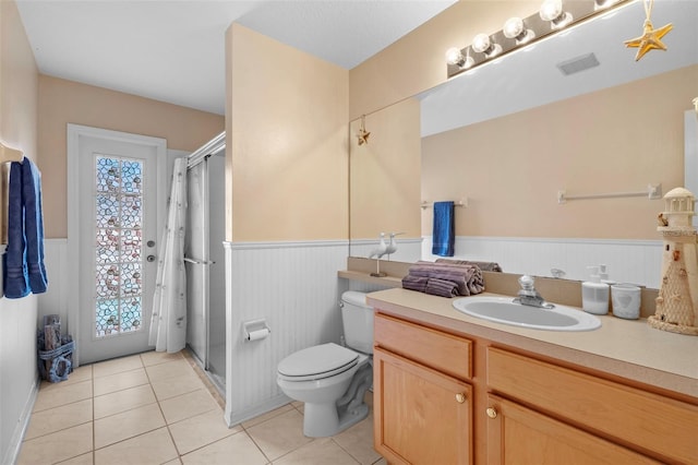 full bathroom with a healthy amount of sunlight, a wainscoted wall, toilet, and tile patterned floors