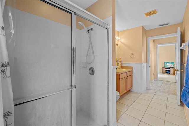 full bathroom featuring tile patterned flooring, a wainscoted wall, vanity, visible vents, and a shower stall