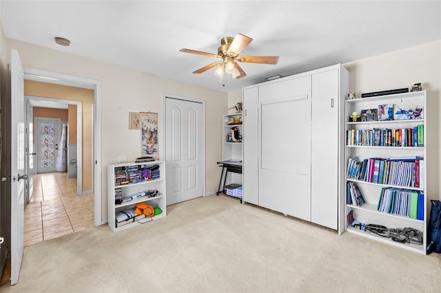 interior space featuring a ceiling fan, light colored carpet, and light tile patterned floors