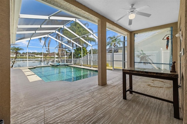 view of swimming pool featuring ceiling fan, glass enclosure, a patio area, and fence