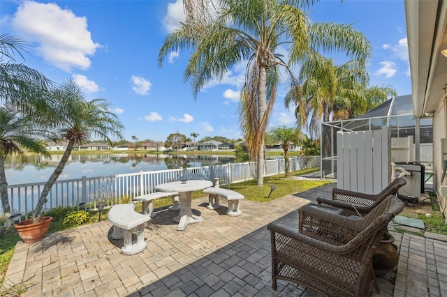 view of patio / terrace with a water view, glass enclosure, and a fenced backyard