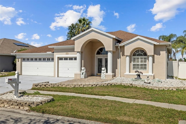 view of front facade featuring french doors, concrete driveway, an attached garage, and stucco siding