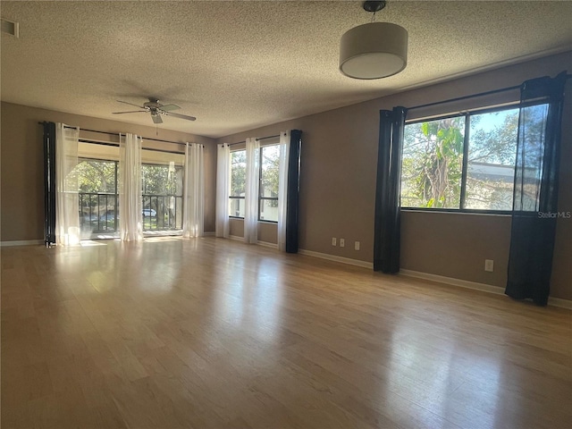 unfurnished room with baseboards, a textured ceiling, a ceiling fan, and wood finished floors