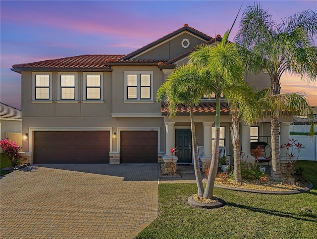 view of front of house featuring a garage, a tile roof, stone siding, decorative driveway, and stucco siding