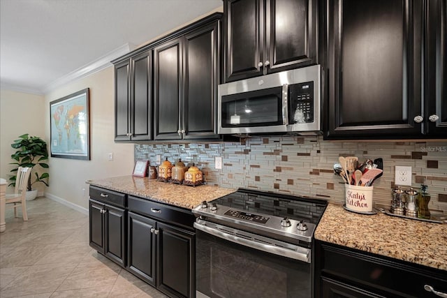 kitchen with light stone counters, ornamental molding, dark cabinets, stainless steel appliances, and backsplash