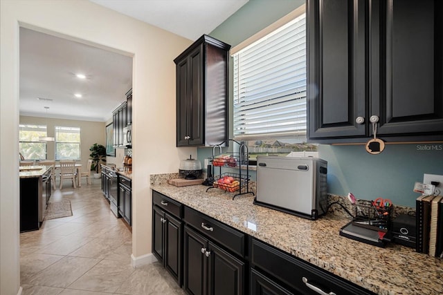 kitchen with light stone counters, light tile patterned floors, stainless steel microwave, dark cabinets, and range