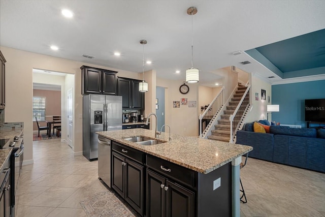 kitchen with visible vents, light stone counters, appliances with stainless steel finishes, open floor plan, and a sink