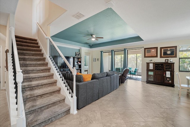 living room featuring a tray ceiling, a ceiling fan, visible vents, and a healthy amount of sunlight