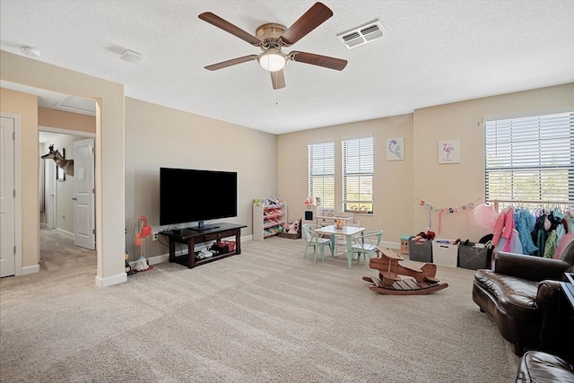 carpeted living area with visible vents, ceiling fan, a textured ceiling, and baseboards