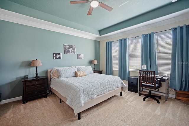 carpeted bedroom featuring baseboards, a raised ceiling, ceiling fan, ornamental molding, and a textured ceiling