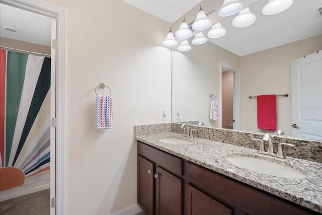 full bath with double vanity, baseboards, visible vents, and a sink