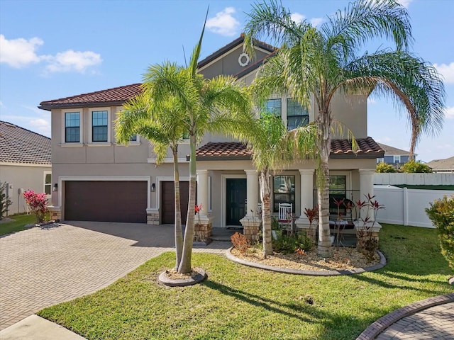 view of front of house with decorative driveway, stucco siding, an attached garage, a front yard, and fence