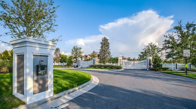 view of road with a gate, a gated entry, and curbs