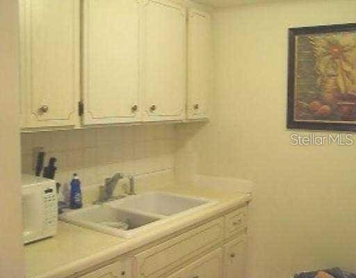 kitchen with white cabinets, tasteful backsplash, light countertops, and a sink