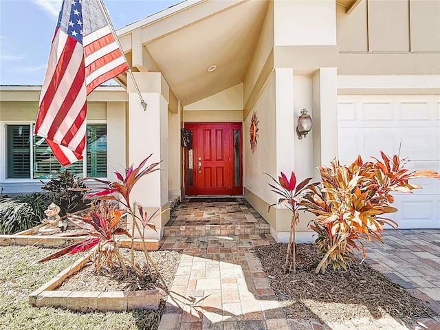 entrance to property with a garage and stucco siding