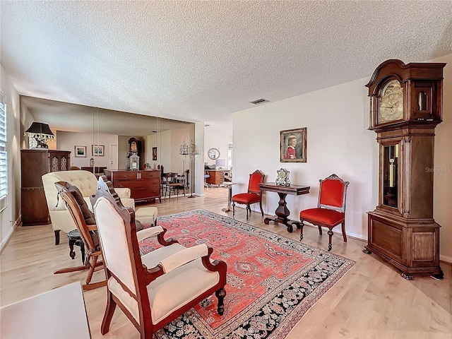 sitting room with a healthy amount of sunlight, light wood finished floors, visible vents, and a textured ceiling