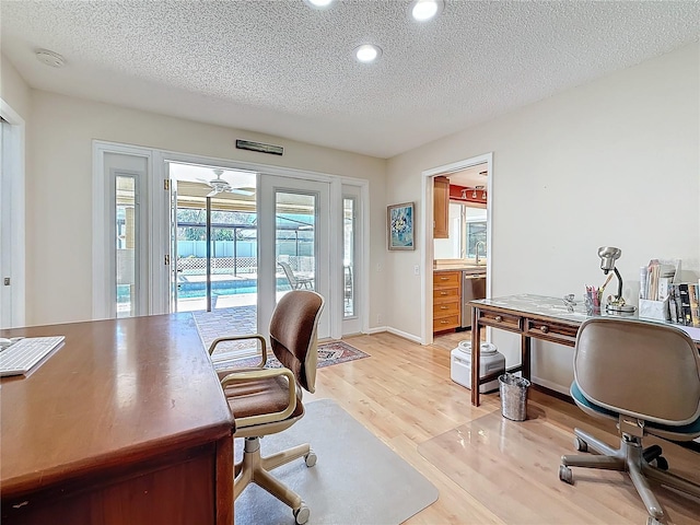 office area featuring a textured ceiling, light wood finished floors, a sink, and recessed lighting