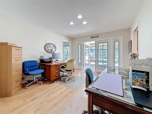 office area with light wood-style floors, a textured ceiling, and recessed lighting