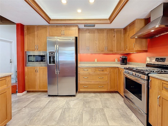 kitchen featuring wall chimney exhaust hood, a tray ceiling, visible vents, and stainless steel appliances