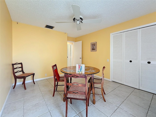 dining room featuring light tile patterned floors, visible vents, a ceiling fan, a textured ceiling, and baseboards