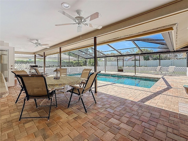 view of swimming pool featuring glass enclosure, ceiling fan, fence, and a patio