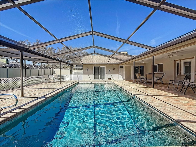 view of swimming pool featuring a patio area, fence, a ceiling fan, and a lanai