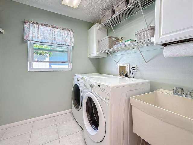 clothes washing area featuring light tile patterned floors, a textured ceiling, a sink, cabinet space, and washing machine and clothes dryer