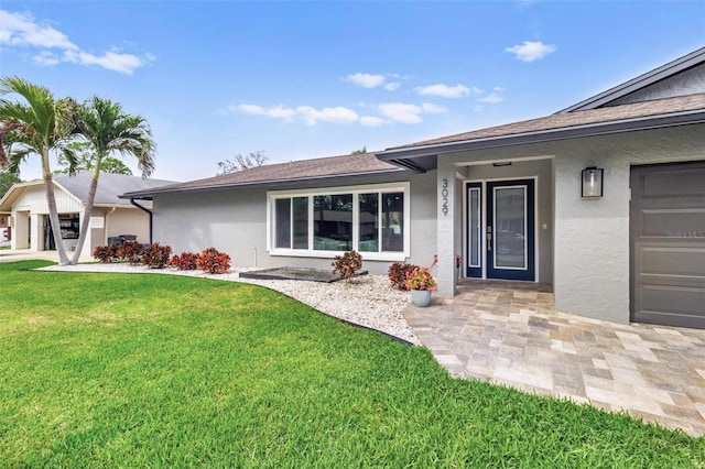 view of front of property with a garage, a front yard, and stucco siding