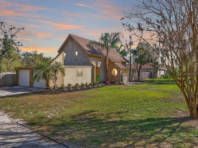 view of front facade with fence, driveway, an attached garage, and a lawn