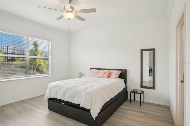 bedroom with baseboards, light wood-style floors, a ceiling fan, and crown molding