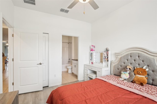 bedroom featuring light wood-style flooring, visible vents, and connected bathroom