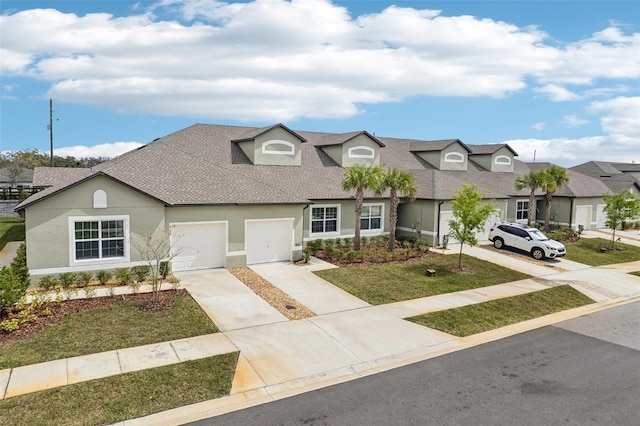 view of front facade with driveway, roof with shingles, an attached garage, a front yard, and stucco siding