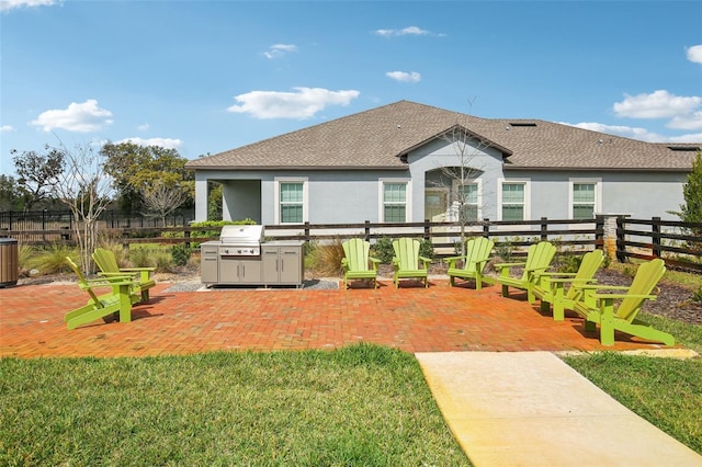 rear view of house featuring a shingled roof, a patio, fence, and stucco siding