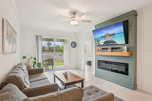 living area with crown molding, a glass covered fireplace, light tile patterned flooring, and ceiling fan