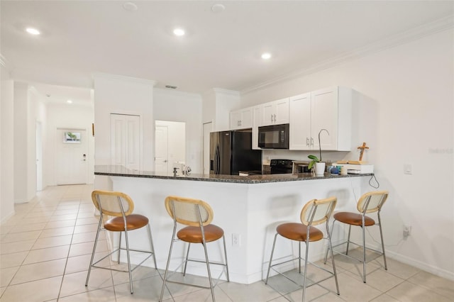 kitchen featuring a kitchen breakfast bar, black appliances, white cabinets, and crown molding