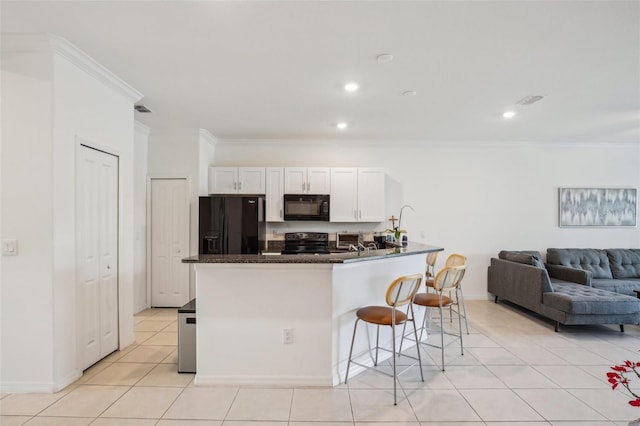 kitchen with light tile patterned flooring, a kitchen breakfast bar, white cabinets, black appliances, and crown molding