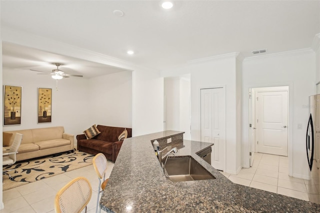 kitchen with crown molding, visible vents, freestanding refrigerator, light tile patterned flooring, and a sink