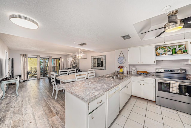 kitchen featuring a peninsula, stainless steel electric stove, white dishwasher, a sink, and light countertops