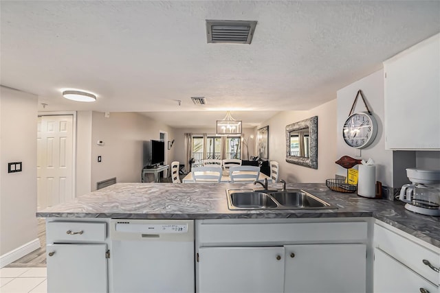 kitchen featuring visible vents, a peninsula, white dishwasher, a textured ceiling, and a sink